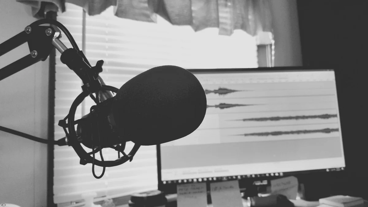 マイクと音声波形が並んだ収録画面のモノクロ写真